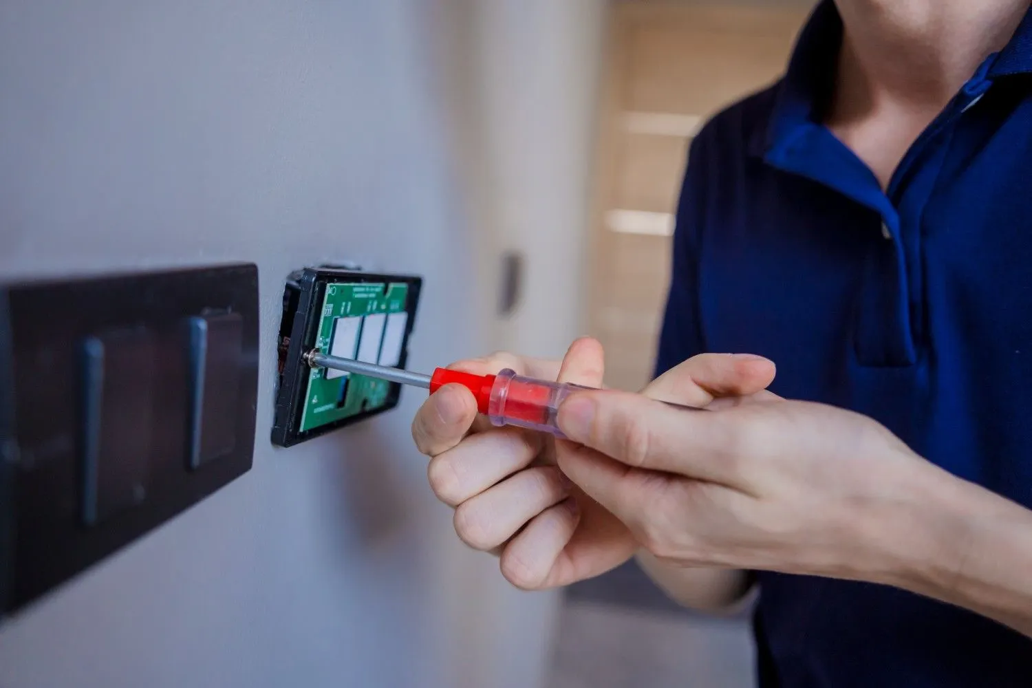 Electrician fitting a wall switch with a screwdriver